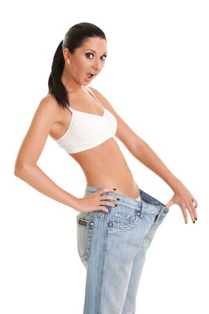 Pretty woman shows her weight loss by wearing an old jeans, isolated on white backgroundの写真素材