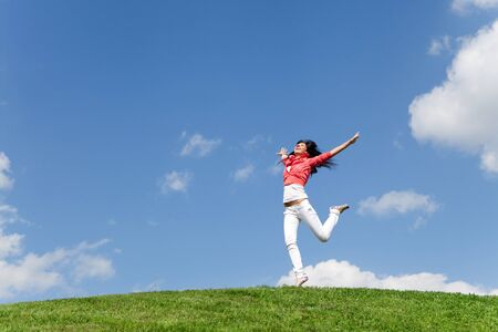 pretty young woman jumping on green grassの写真素材