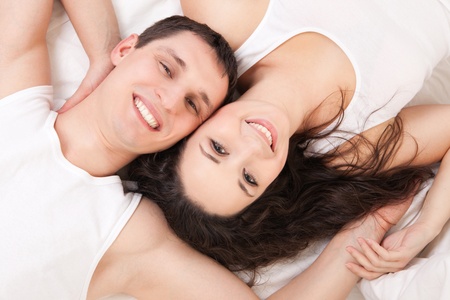 Young happy couple lying in the white bedの写真素材