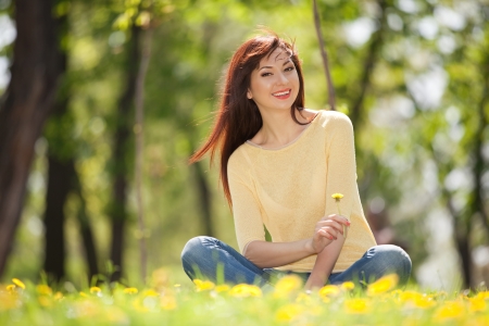 Young happy woman in the park with flowersの写真素材