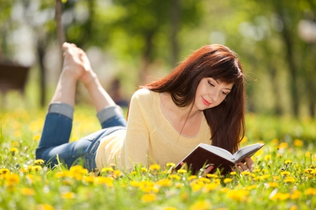 Young woman reading a book in the park with flowersの写真素材