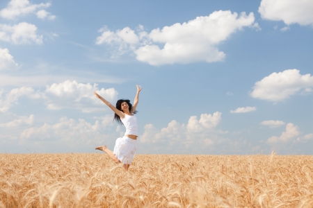 Happy woman jumping in golden wheatの写真素材