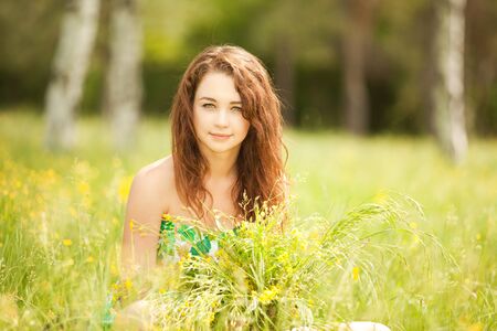 Young redhead woman in the park with flowersの写真素材