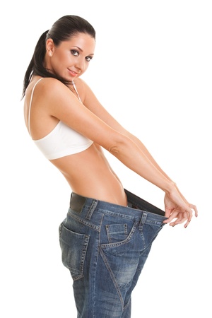 Pretty woman shows her weight loss by wearing an old jeans, isolated on white backgroundの写真素材