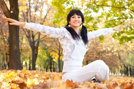 Pretty woman doing yoga exercises in the autumn parkの写真素材