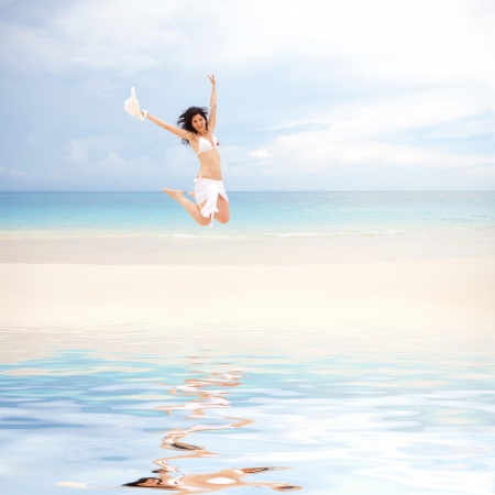 happy young woman jumping on the beach of seaの写真素材