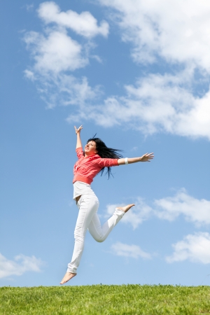 pretty young woman jumping on green grassの写真素材