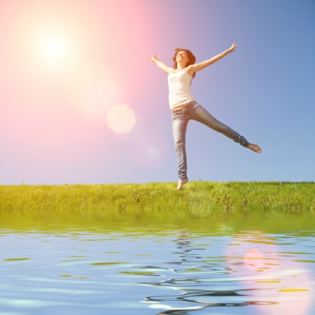 pretty young woman jumping on green grass の写真素材