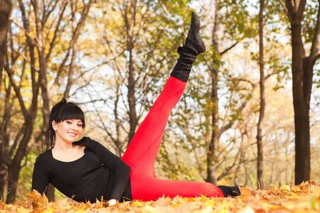 Pretty woman doing sport exercises in the autumn parkの写真素材
