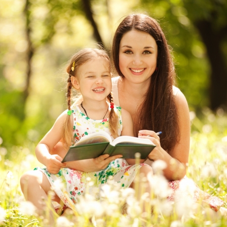 Mother and daughter drawing on grass in parkの写真素材