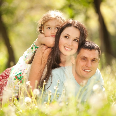 Happy mother, father and daughter in the parkの写真素材