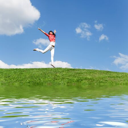 pretty young woman jumping on green grassの写真素材