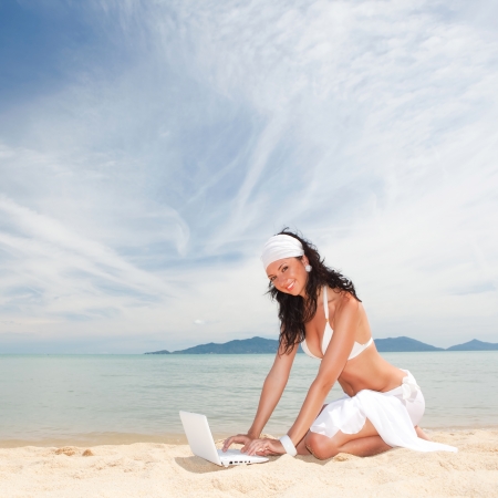 Cute woman with white laptop on the summer beachの写真素材