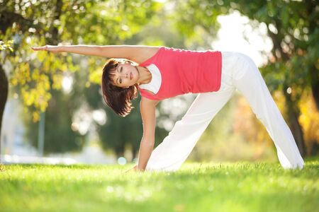 Pretty woman doing yoga exercises in the parkの写真素材