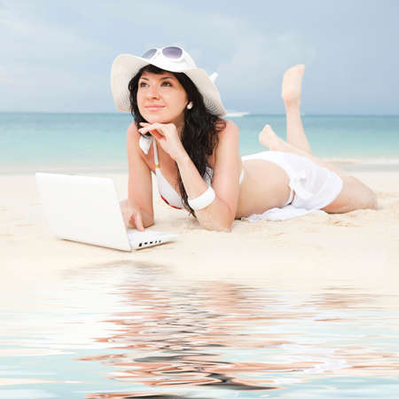 Cute woman with white laptop on the summer beachの写真素材
