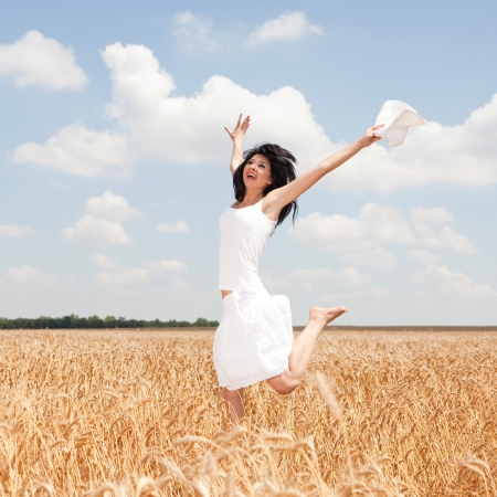 Happy woman jumping in golden wheatの写真素材