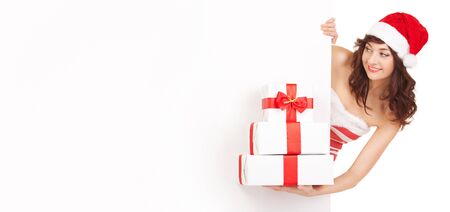 Santa woman with gift boxes looking at white blank boardの写真素材