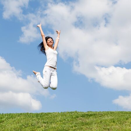 pretty young woman jumping on green grassの写真素材
