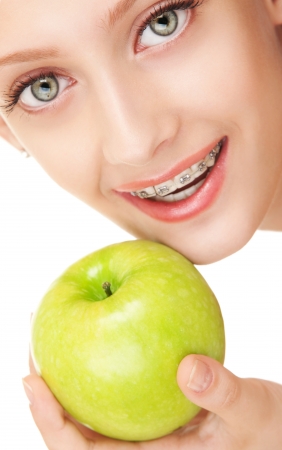 Cute girl in braces with green apple on white backgroundの写真素材