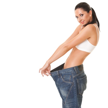 Pretty woman shows her weight loss by wearing an old jeans, isolated on white backgroundの写真素材