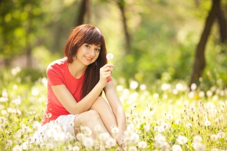Cute woman in the park with dandelionsの写真素材