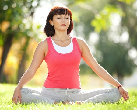 Pretty woman doing yoga exercises in the parkの写真素材