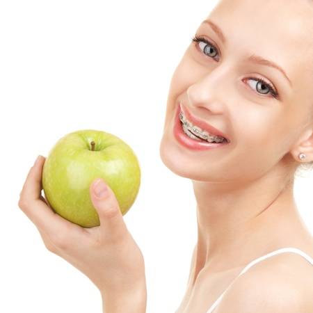 Cute girl in braces with green apple on white backgroundの写真素材