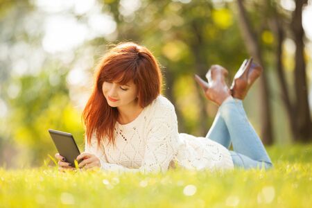 Young pretty woman with tablet in the parkの写真素材
