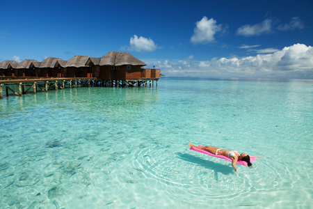 Woman swim and relax on inflatable mattress in the sea. Happy island lifestyle. White sand, crystal-blue sea of tropical beach. Vacation at Paradise. Ocean beach relax, travel to Maldives islandsの写真素材