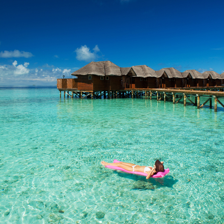 Woman swim and relax in the sea. Happy island lifestyle. White sand, crystal-blue sea of tropical beach. Vacation at Paradise. Ocean beach relax, travel to Maldives islandsの写真素材