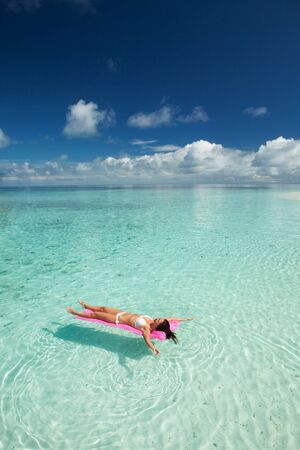 Woman swim and relax in the sea. Happy island lifestyle. White sand, crystal-blue sea of tropical beach. Vacation at Paradise. Ocean beach relax, travel to Maldives islandsの写真素材