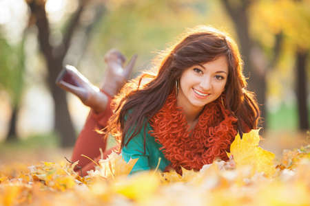 Young pretty woman relaxing in the autumn park. Beauty nature scene with colorful foliage background, yellow trees and leaves at fall season. Autumn outdoor lifestyleの写真素材