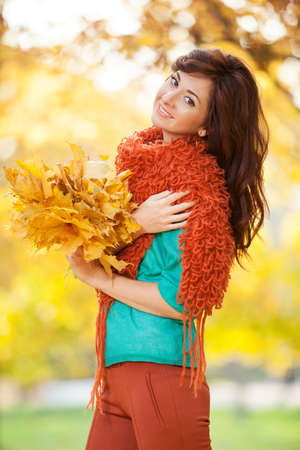 Young pretty woman relaxing in the autumn park. Beauty nature scene with colorful foliage background, yellow trees and leaves at fall season. Autumn outdoor lifestyleの写真素材