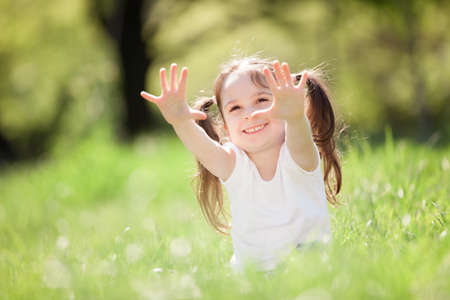 Cute little girl play in the park. Beauty nature scene with colorful background at summer or spring season. Family outdoor lifestyle. Happy girl relax on green grassの写真素材
