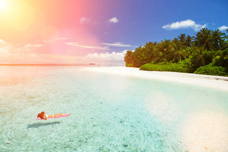 Woman swim and relax in the sea. Happy island lifestyle. White sand, crystal-blue sea of tropical beach. Vacation at Paradise. Ocean beach relax, travel to Maldives islandsの写真素材