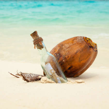 A letter in a bottle and coconut on the beach. Island lifestyle. White sand, crystal-blue sea of tropical beach. Ocean beach relax, travel to islandsの写真素材