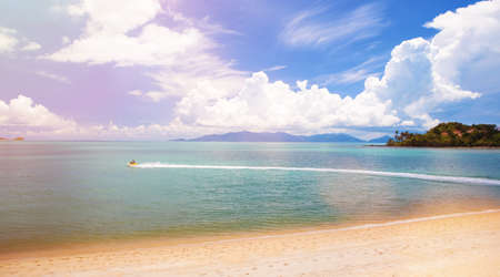 Beautiful tropical seascape. Ocean waves and cloudy sky background. Crystal-blue sea, island, water bike. Ocean water nature, beach relax. Summer sea vacationの写真素材