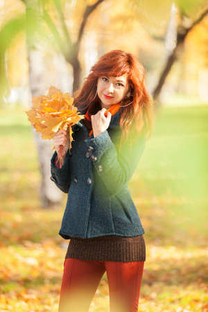 Young pretty woman relaxing in the autumn park. Beauty nature scene with colorful foliage background, yellow trees and leaves at fall season. Autumn outdoor lifestyleの写真素材