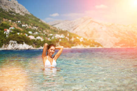 Happy fashion woman relax on the summer beach. Blue sky, beautiful mountains and crystal sea. Happy lifestyle. Vacation at Europeの写真素材