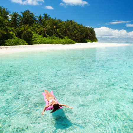 Woman swim and relax in the sea. Happy island lifestyle. White sand, crystal-blue sea of tropical beach. Vacation at Paradise. Ocean beach relax, travel to Maldives islandsの写真素材