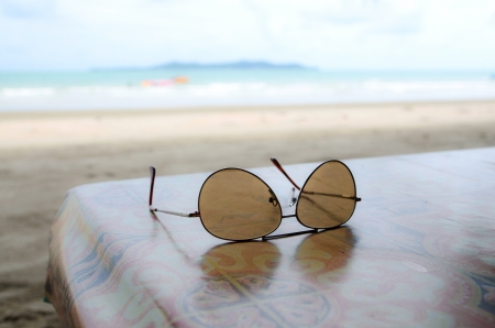 Sunglasses  on table shore of beach in Thailandの写真素材