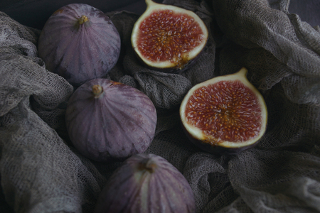 Figs on dark fabric in a wooden box on a dark stone background, Selective focus