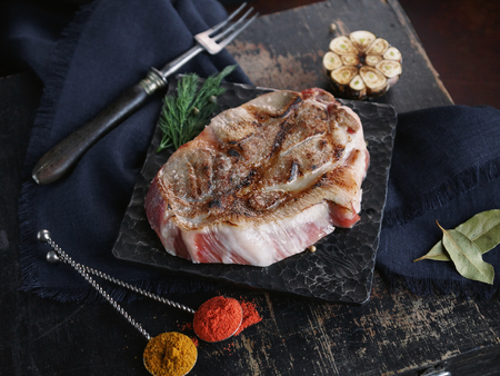 Fried meat on a wooden board with metal cookware on dark stone backgroundの写真素材