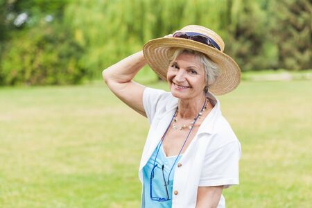 best ager women posing outdoors with hatの写真素材