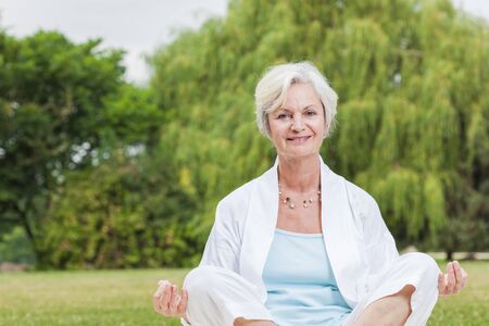 best ager women practising yoga and tai chi outdoorsの写真素材
