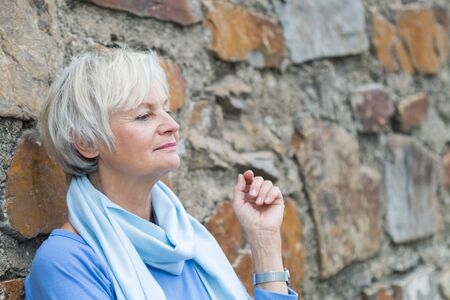confident natural senior women posing at brick wallの写真素材