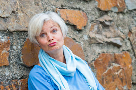 confident natural senior women posing at brick wallの写真素材