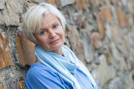 confident natural senior women posing at brick wallの写真素材