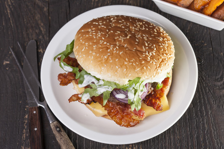 juicy  bacon cheese bbq burger on wooden table with friesの写真素材