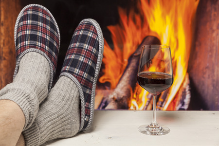 relaxing in slippers at fireplace white table with red wineの写真素材